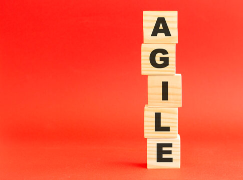 Wooden cubes with word AGILE. Wooden cubes on a red background. Free space on the left.