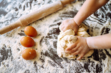 Children hands kneading dough on wooden table. Easter baking preparation. Cookies for Christmas....