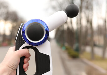 Hand holding a therapeutic percussive massage gun.