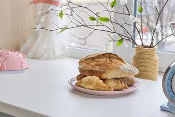 Freshly baked bread and croissants on plate near the window