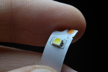 a person's fingers are holding a piece of 12 volt LED strip. close-up