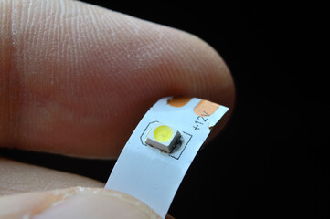 a person's fingers are holding a piece of 12 volt LED strip. close-up