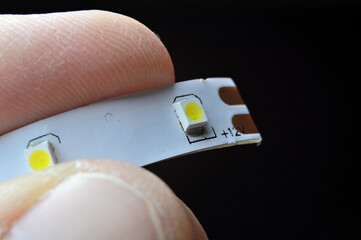 a person's fingers are holding a piece of 12 volt LED strip. close-up