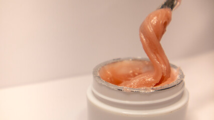 Pink cream in a white jar on a light background