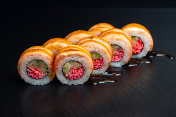 japanese food, rolls with tuna, unagi sauce and surimi filling on black background