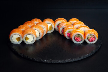Japanese food, a set of rolls with salmon, Philadelphia cottage cheese, orange, cucumber, surimi on a black background