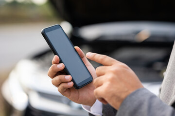Young asian business has broken down car. He open hood and check the engine. He using smartphone call for help and service. Car broken on the side of the road