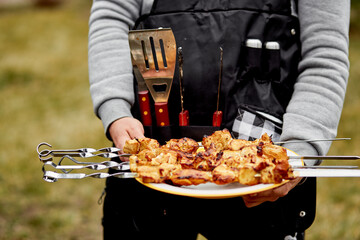 Backyard picnic. Man serving hot kebab with barbecue tools