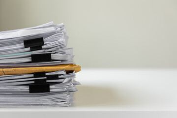 Piles of white papers work large piles of papers stacked together. On the desk in the office with black clip. Documents that are not finished. Business concept.