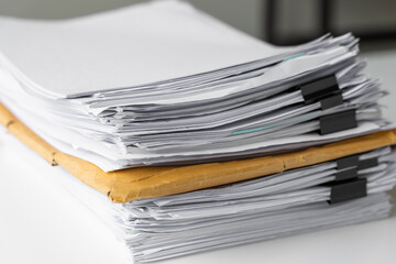 Piles of white papers work large piles of papers stacked together. On the desk in the office with black clip. Documents that are not finished. Business concept.