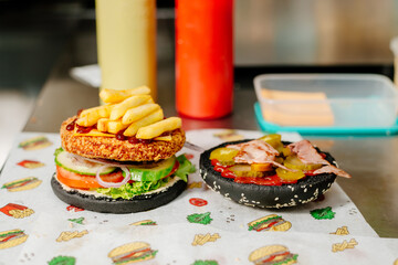 The process of making a chicken burger with fries in a black bun. The chef prepares a chicken burger with fries. Cooking burgers in the diner kitchen.