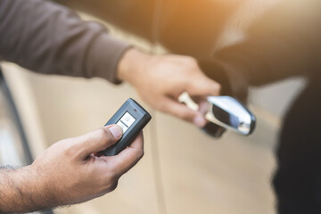 Close up male hand holding car key. Man unlock car door by remote key push button near car door.