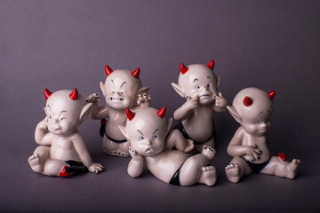 The cute emotional devils statues on the deep grey background