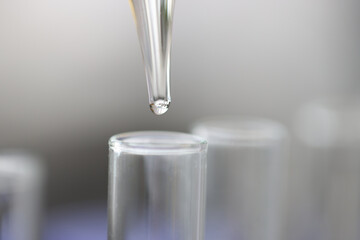 Clear liquid drips from pipette into test tube
