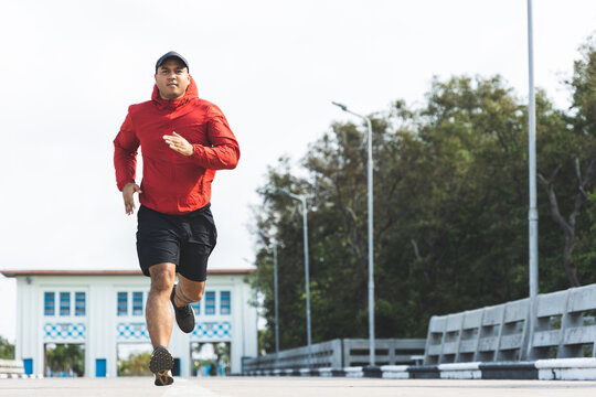 Young Asian Man Wearing Sportswear Running Outdoor. Portraits Of Indian Man Jogging On The Road. Training Athlete Outdoor Concept.