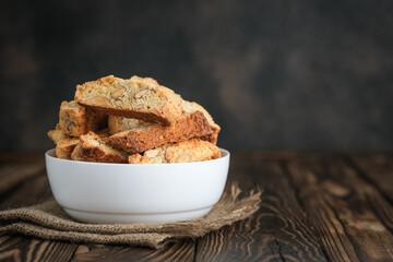 Cantuccini biscotti with almonds on a white bowl on a rustic background with copy space.