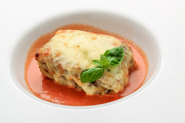 Close-up of a traditional lasagna made with minced beef bolognese sauce topped with basil leafs served