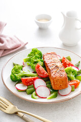 Salmon fish fillet grilled and vegetable salad with radish, tomato, green pepper, broccoli and asparagus.