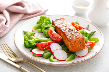 Salmon fish fillet grilled and vegetable salad with radish, tomato, green pepper, broccoli and asparagus.