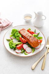 Salmon fish fillet grilled and vegetable salad with radish, tomato, green pepper, broccoli and asparagus.