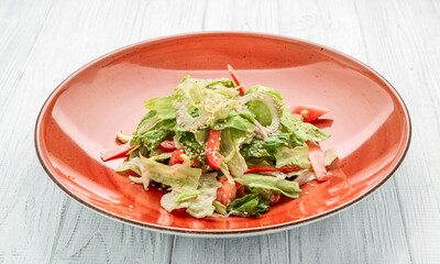 Fresh vegetable salad of chinese cabbage, tomato, pepper and onion with olive or sunflower oil on wooden table.