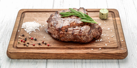 grilled beef steaks with spices on wooden cutting board