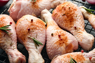 Raw chicken drumsticks with ingredients for cooking on a black stone background. Food background, Raw meat with spices at black table. Top view.