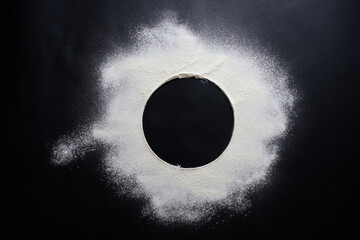 Abstract background. Sprinkled wheat flour circle, round spot on black. Top view on blackboard....
