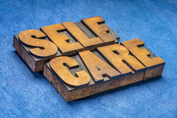 self care word abstract in vintage letterpress wood type against blue  handmade paper - mental,...