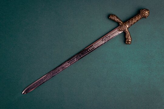 Antique knightly sword on a green velvet background. Copy space