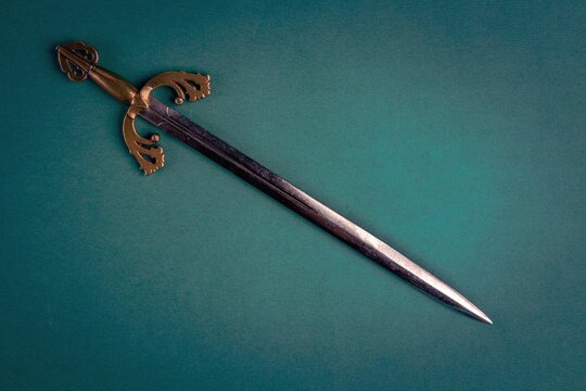 Antique knightly sword on a green velvet background. Copy space