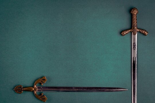 Two old knightly swords on a green velvet background.