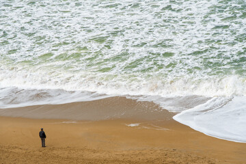 Homme debout regardant la mer depuis la plage