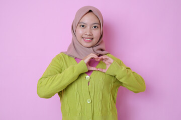 Young Muslim Asian woman showing romantic shapes heart gesture expresses tender feelings wears...