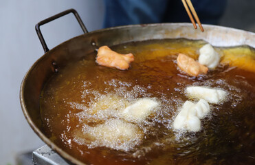 Closeup of fresh oriental dough, doughnuts frying in  hot oil pan.