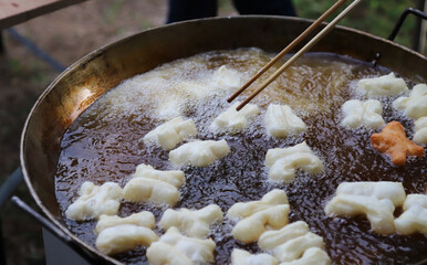 Closeup of fresh oriental dough, doughnuts frying in  hot oil pan.