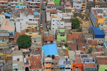 Fototapeta premium Top view of the Indian town. Roofs of houses, urban buildings, houses and cars in a small Indian city. Tiruchchirapalli from a bird's eye view.