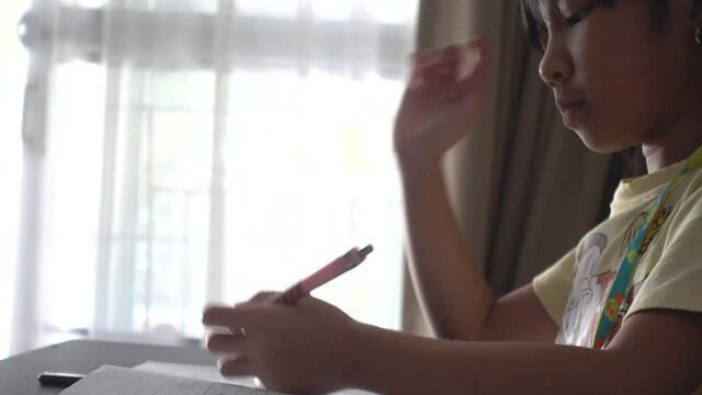 Asian child girl sitting at home studying and writing during the epidemic covid-19.