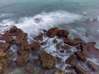 Aerial top view of sea waves hitting rocks.