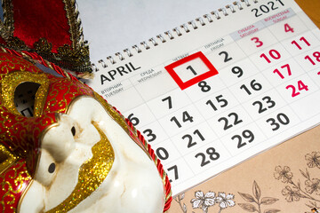 venetian jester mask, and calendar on a pink background, concept photo for april 1, fools day,...