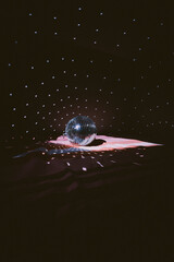 Illuminated by sun light silver disco mirror ball. Dark black background and cold blue and purple...