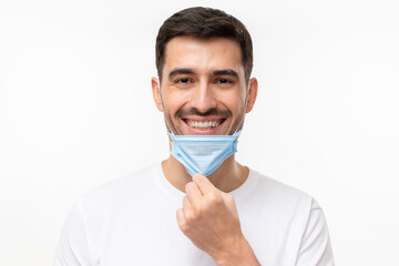 Smiling young man taking off medical mask after the end of pandemic. Concept of future, hope and...