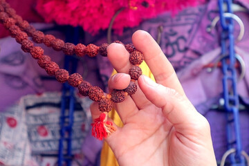 A girl is holding a rosary from Rudraksh in an Indian souvenir shop.