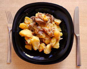 stewed chicken with potatoes in a black plate
