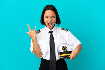 Young airplane pilot over isolated blue background making horn gesture © luismolinero