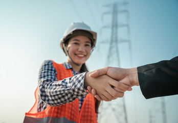 Happy woman engineer worker handshake with business people and electric pole blue sky background