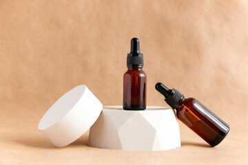 Creative still life with amber glass cosmetic bottles on a concrete podium against a background of kraft paper. Spa and skin care concept.