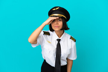 Young airplane pilot over isolated blue background looking far away with hand to look something