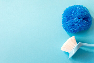 Blue monochrome flay lay with copy space for your text on the left of brush, and sponge for cleaning.