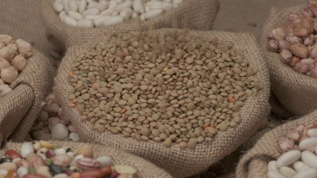 Dry lentils legumes falling on jute bowl. Mediterranean diet, vegan vegetarian ingredient healthy protein food